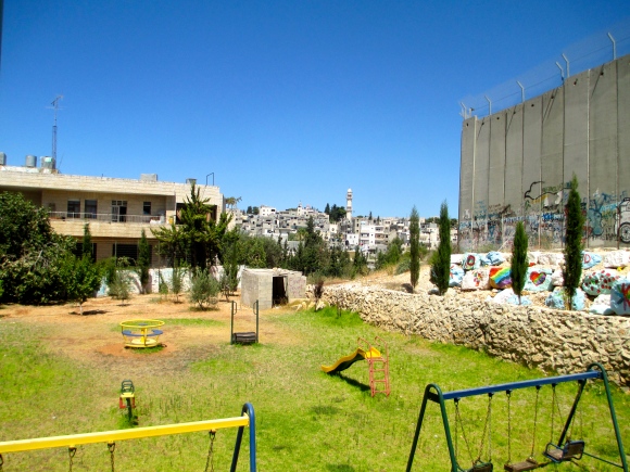 The tension between a children's playground and the separation barrier sitting right next to each other...